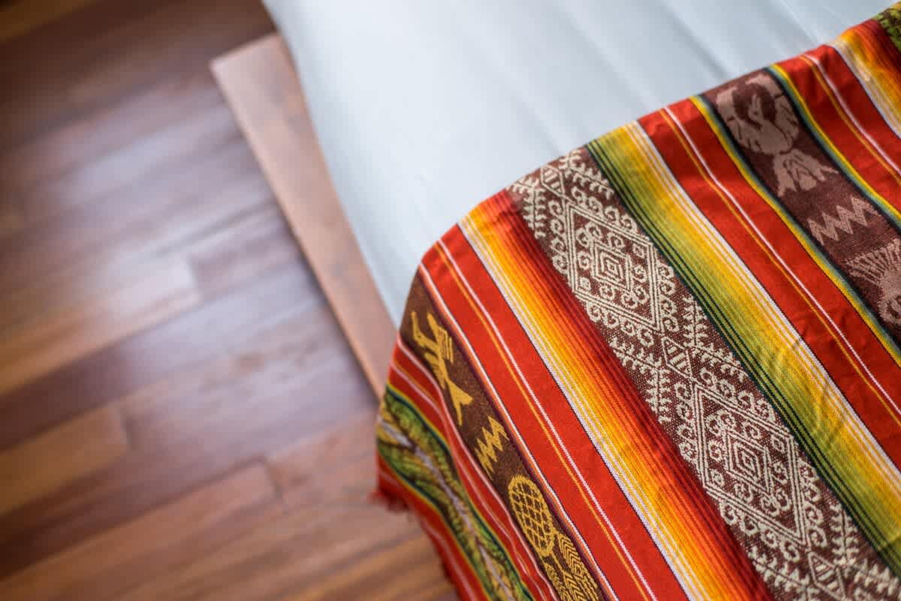 Una cama con un edredón colorido y piso de madera.