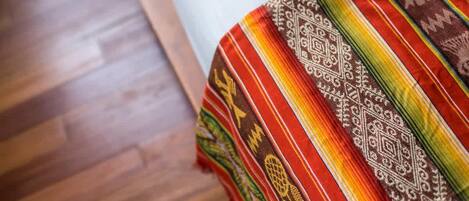 A bed with a colorful blanket and a wooden floor.