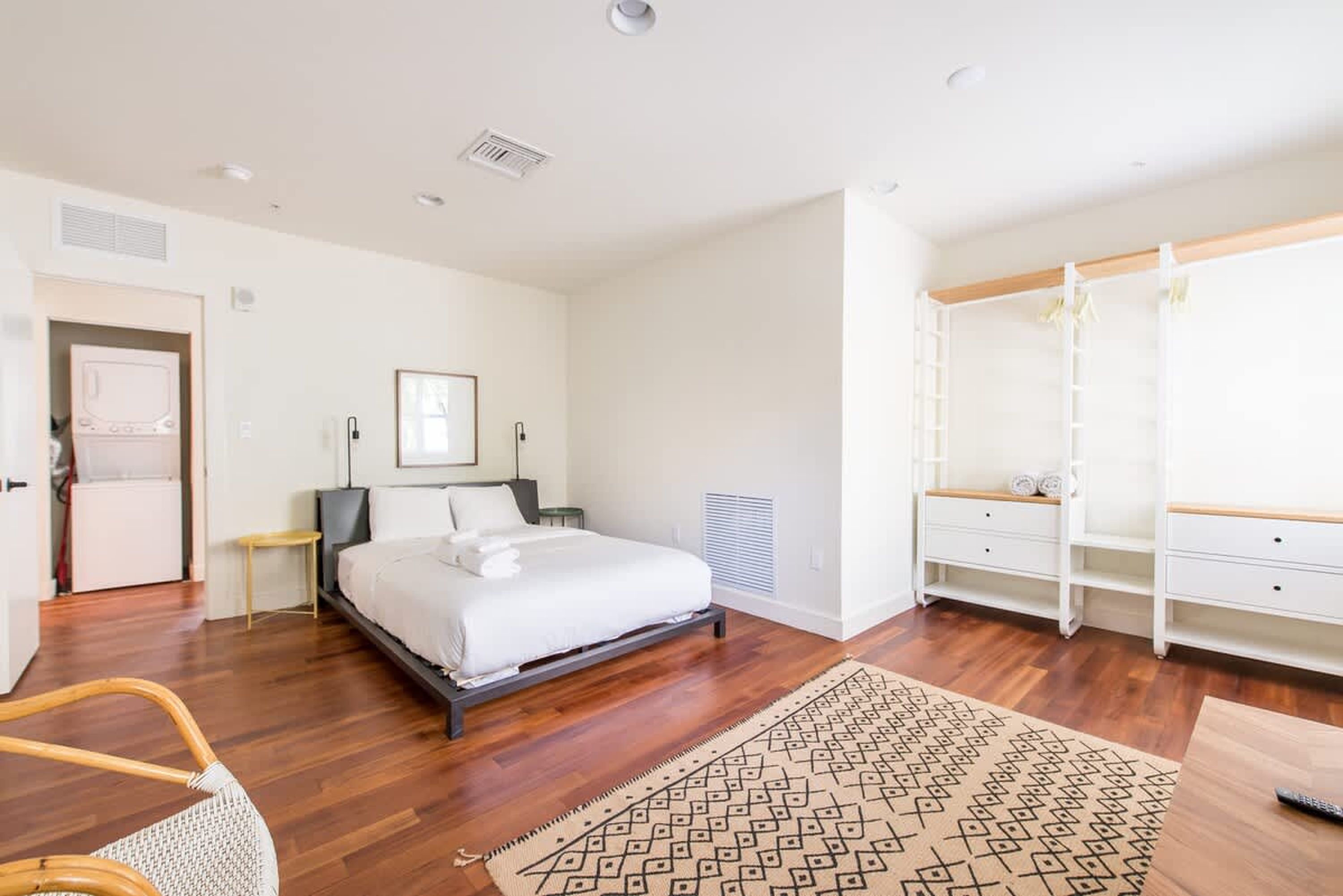 A modern bedroom with a bed, bedside tables, a wardrobe, and a patterned rug.