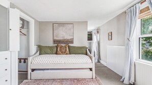 Un dormitorio con cama, un cuadro, una ventana con cortinas y un radiador.