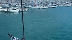 A marina with numerous sailboats docked, a prominent sailboat in the foreground, and a mountainous backdrop. - Central Alicante Apart | Walk to the Beach (Alicante (Alacant))
