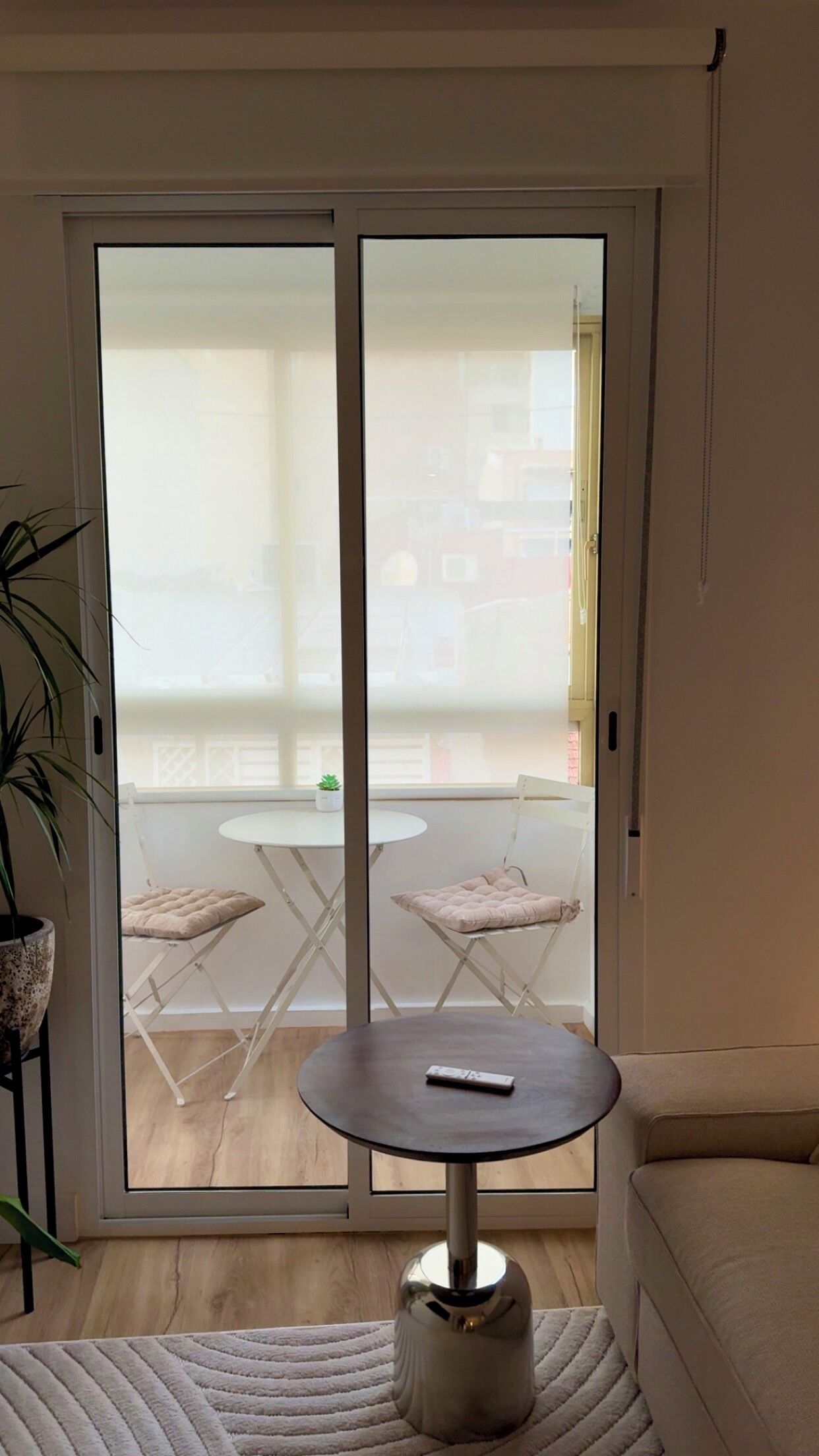 Una habitación con puerta corrediza de vidrio que da a un espacio exterior con mesa y sillas.
