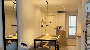 A modern living room with a sofa, a round chair, a dining table with chairs, and a kitchen area in the background. - Central Alicante Apart | Walk to the Beach (Alicante (Alacant))
