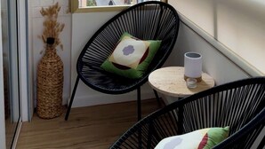 A balcony with two black wire chairs, a small round table with a white mug, and a view of colorful buildings. - Central Alicante Apart | Walk to the Beach (Alicante (Alacant))