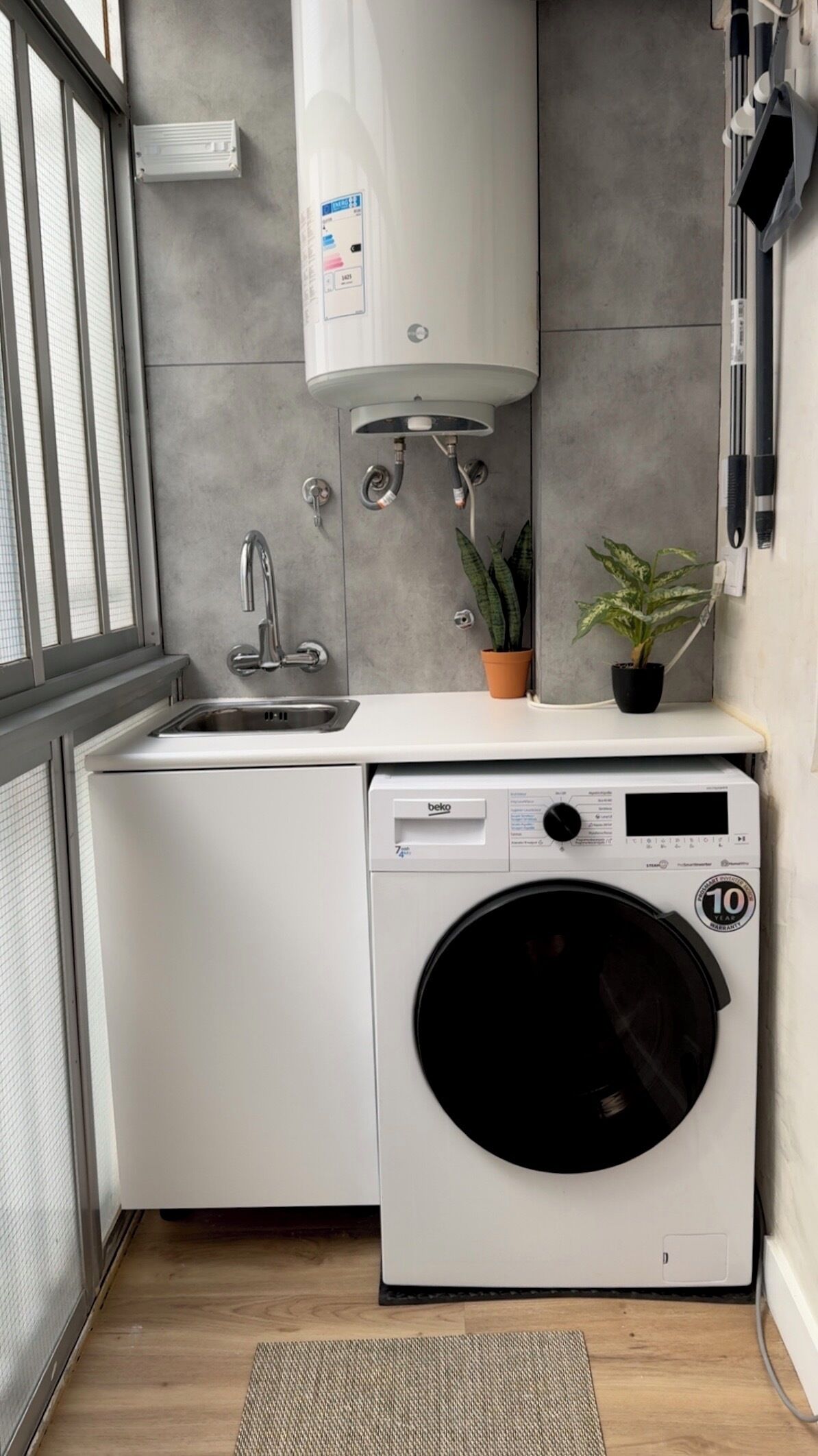 Een kleine keuken met een inbouw wasmachine, een spoelbak en een kleine potplant.