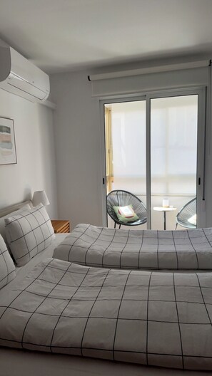 Ein Schlafzimmer mit Bett, Sessel und Tisch neben einer Schiebetür.