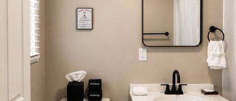 A bathroom with a toilet, sink, mirror, and towel rack.