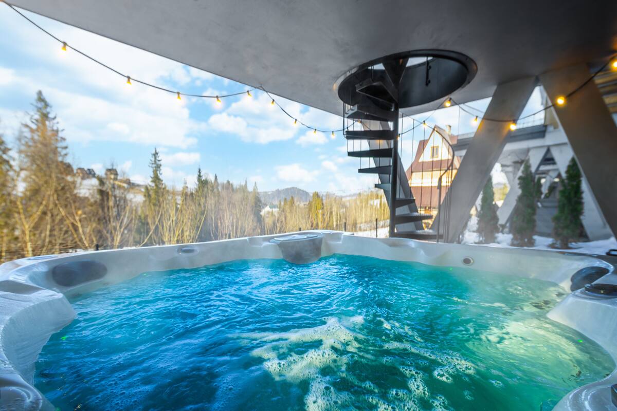 Un jacuzzi con vistas despejadas del paisaje circundante, incluyendo árboles y un edificio al fondo.