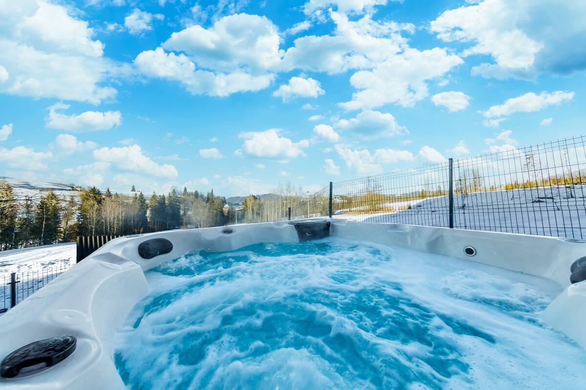 Un jacuzzi con vista a un paisaje nevado y árboles.