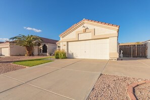 A residential house with a garage, a well-maintained lawn, and a palm tree. - Desert Dame, cool play pool & Patio Family Friendly sleeps 9. (Mesa)