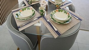 En matplats med ett glasbord, grå stolar och porslin med tropiskt tema.