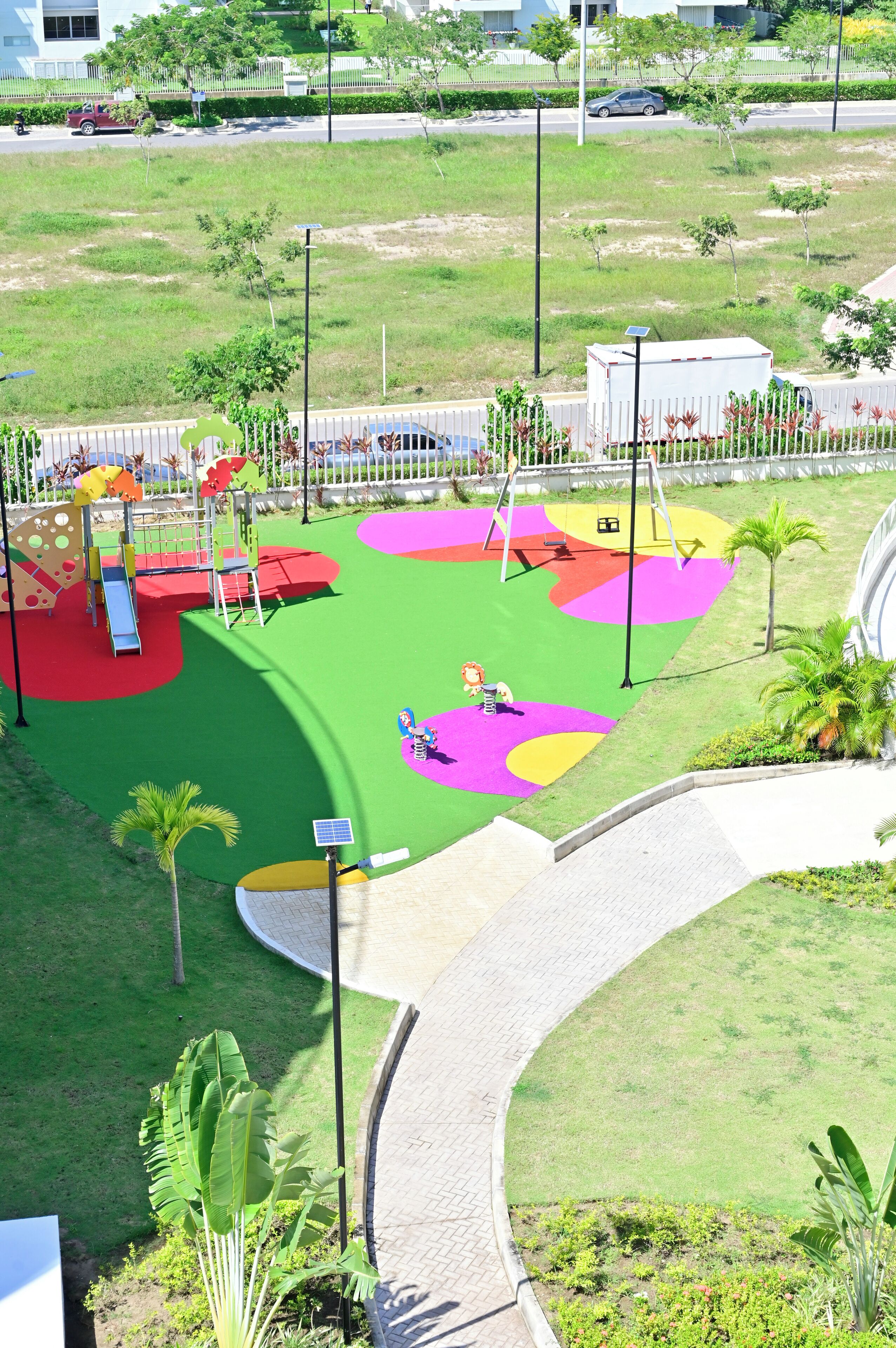 Un parque infantil con zonas de juego coloridas y un sendero.