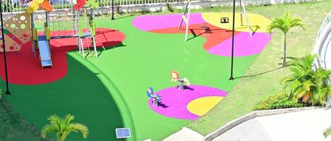 Un parque infantil con zonas de juego coloridas y un sendero.