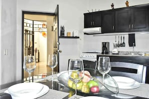 Comedor con una mesa dispuesta para dos personas, un frutero y copas de vino.