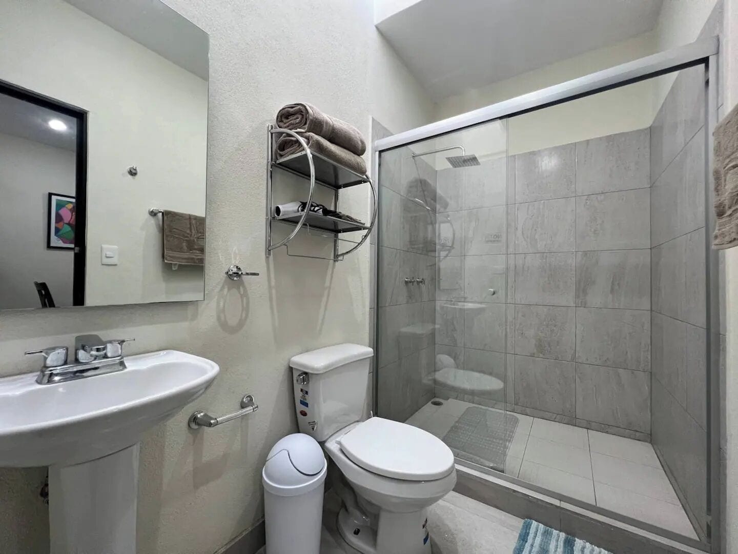 A modern bathroom with a glass shower enclosure, a white sink, and a toilet.