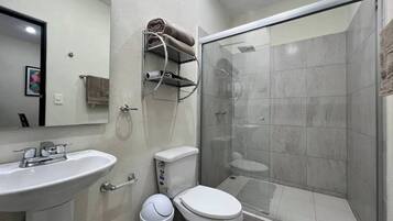 A modern bathroom with a glass shower enclosure, a white sink, and a toilet.
