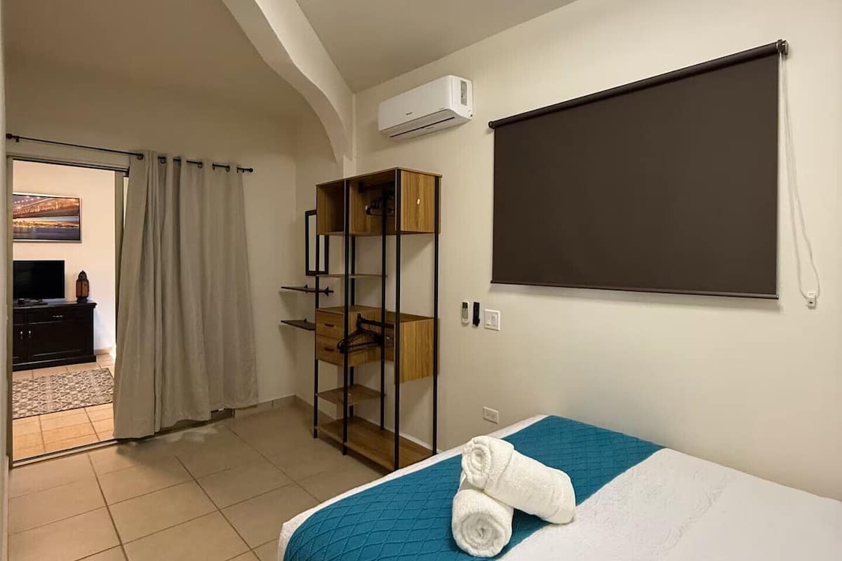 Une chambre d’hôtel avec un lit, une armoire, un bureau et une grande fenêtre.