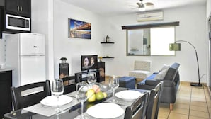 A modern living room with a dining area, a kitchen with a microwave, and a large window. - Cabo Downtown Studios (Cabo San Lucas)