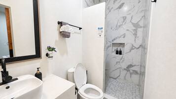 A bathroom with a white sink, toilet, and shower.