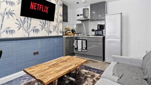 Uma cozinha moderna com forno embutido, geladeira e televisão na parede exibindo 'NETFLIX'.