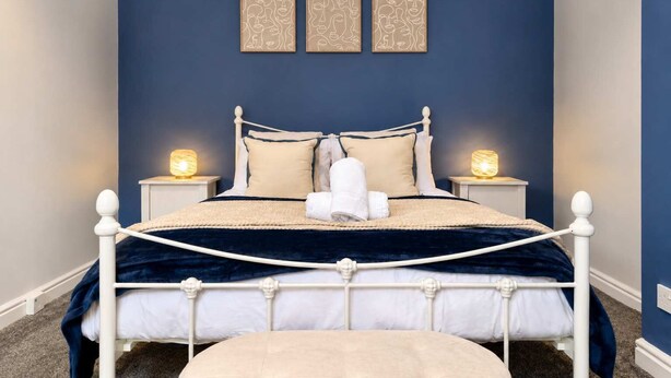 A bedroom with a bed, two bedside tables with lamps, a headboard, and three wall-mounted artworks.
