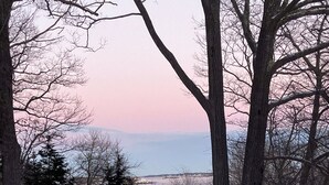 A snowy landscape with trees and a view of a body of water. - The Boat Berth on Peaks Island (Portland)