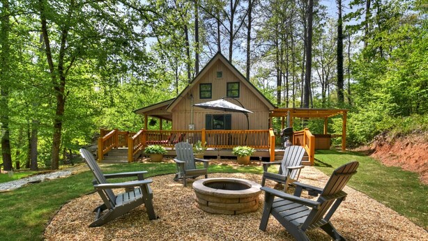 A cabin with a deck, outdoor seating, and a fire pit.