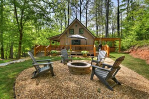 A cabin with a deck, outdoor seating, and a fire pit.