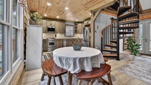 A kitchen with wooden cabinets, a round table with a white tablecloth, and a spiral staircase.