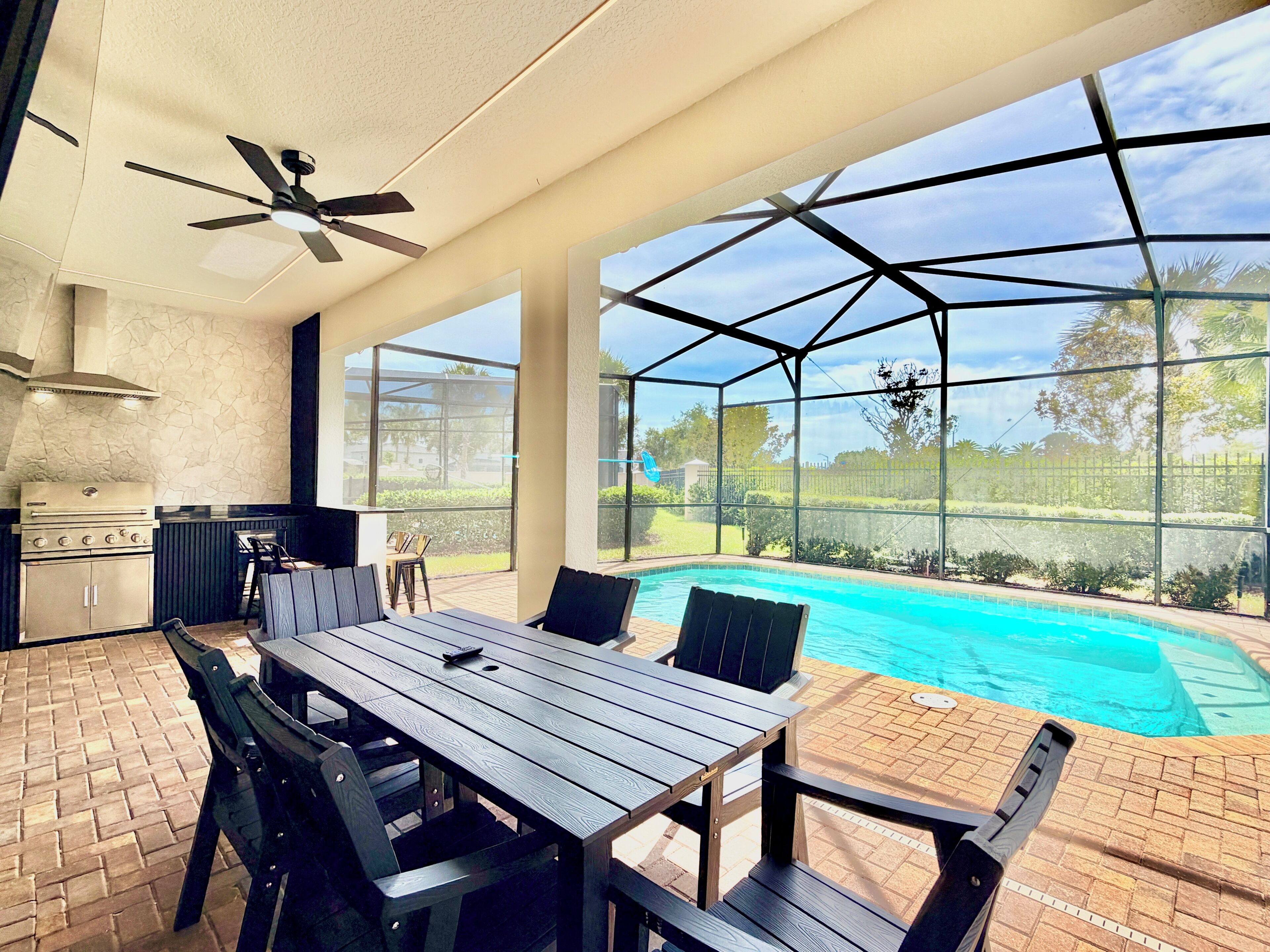 A patio area with a pool, a grill, and a ceiling fan.