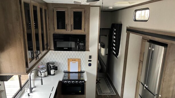 Una cucina compatta con mobili in legno, un forno a microonde, una macchina per il caffè e un fornello.