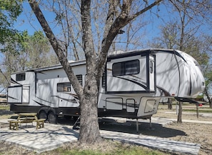 Una caravana Sabre Cobalt estacionada en un camping, con mesas de picnic cerca.