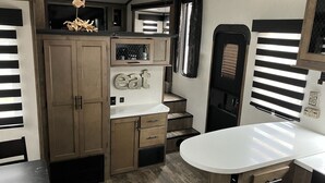 Cucina compatta per camper con lavello integrato, un piano di lavoro e un cartello con la scritta 'eat'.
