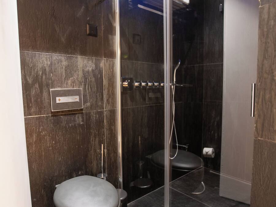 A modern bathroom with a glass-enclosed shower, a toilet, and a towel rack.