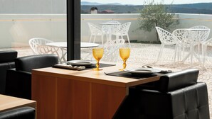 A dining area with a wooden table and chairs, two golden goblets, and a view of the landscape. - Foz Côa Story House (Vila Nova de Foz Côa)