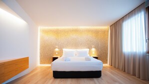 A modern hotel room with a large bed, wooden flooring, a textured wall, and a large window with curtains. - Foz Côa Story House (Vila Nova de Foz Côa)