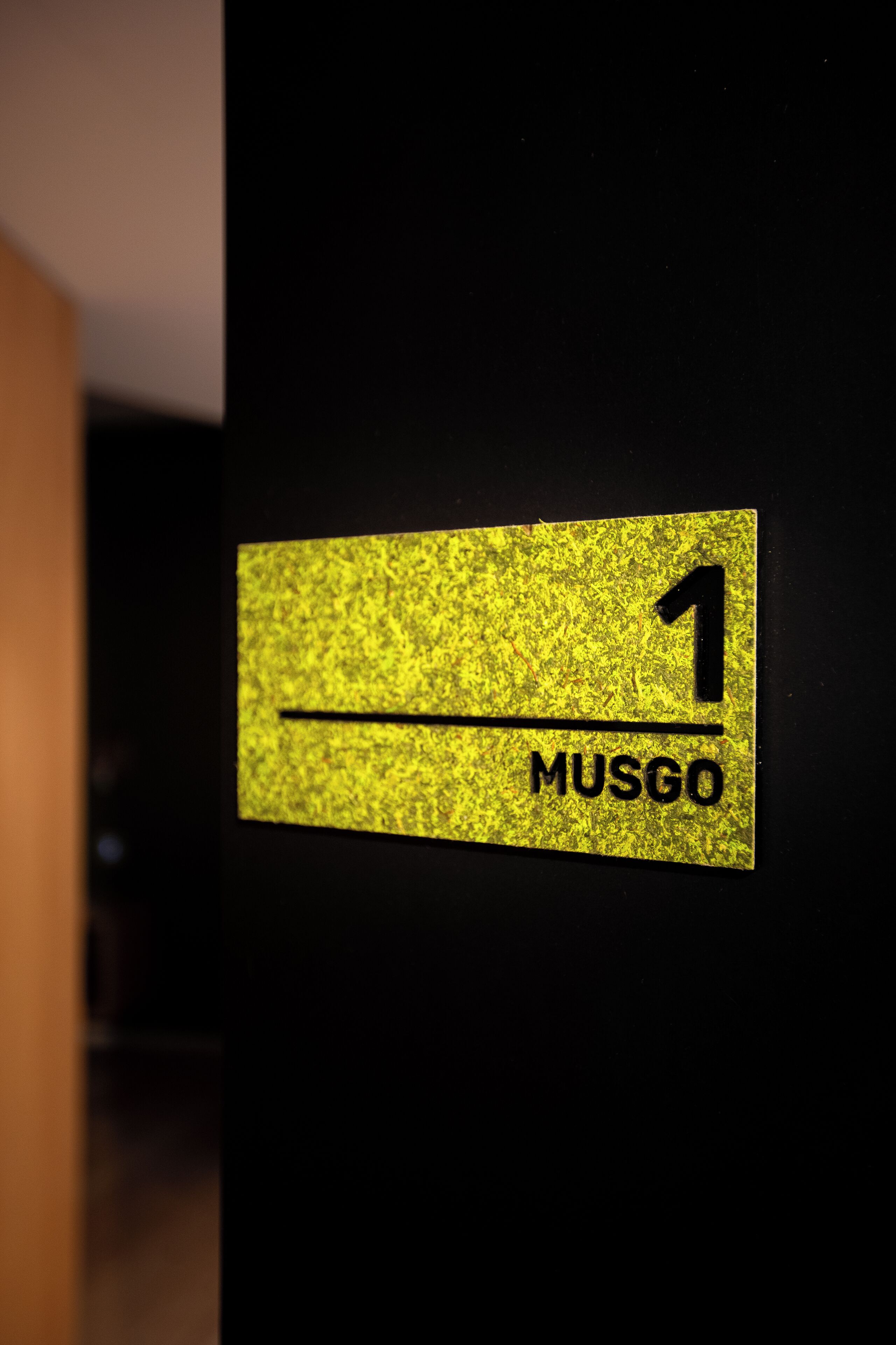 Un panneau jaune portant le chiffre 1 et le mot « MUSGO » sur un fond noir.