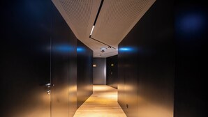 A modern hallway with a wooden floor, dark walls, and a ceiling with a perforated pattern. - Foz Côa Story House (Vila Nova de Foz Côa)