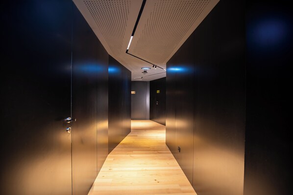 A modern hallway with a wooden floor, dark walls, and a ceiling with a perforated pattern. - Foz Côa Story House (Vila Nova de Foz Côa)