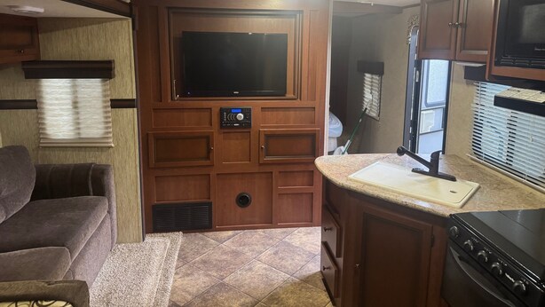 A compact RV kitchen with a built-in microwave, stove, and a small countertop. - Your Peaceful Waterfront Getaway Camping/Fishing Experience with Country Living (Pineview)