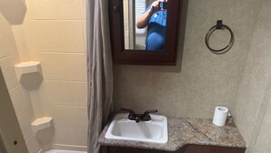 A bathroom with a white sink, a mirror, a towel ring, and a toilet. - Your Peaceful Waterfront Getaway Camping/Fishing Experience with Country Living (Pineview)