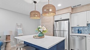 A modern kitchen with a central island, stainless steel appliances, and a blue accent wall. - Private Beach + Chair Service/Pool/Bikes (Santa Rosa Beach)