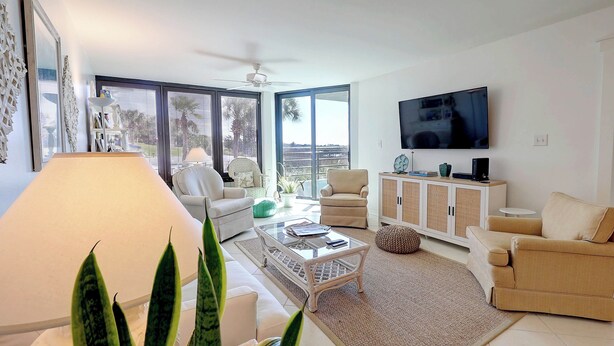 A modern living room with a sofa, armchair, coffee table, and a TV on a wall. - Ground Floor Condo with Shared Pool, Golf Access, Bay Views, and WiFi (Panama City)