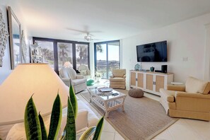 A modern living room with a sofa, armchair, coffee table, and a TV on a wall. - Ground Floor Condo with Shared Pool, Golf Access, Bay Views, and WiFi (Panama City)