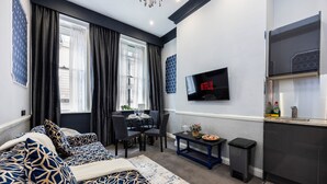 A modern living room with a sofa, dining table, and a TV mounted on the wall. - Stunning Super king & Double Bed Apartment|Central London|Oxford St|Bond St (London)