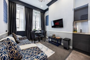 A modern living room with a sofa, dining table, and a TV mounted on the wall. - Stunning Super king & Double Bed Apartment|Central London|Oxford St|Bond St (London)