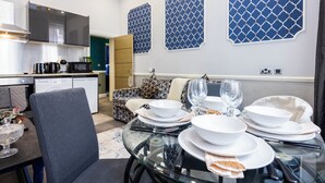 A modern kitchen with built-in appliances, a dining area with a glass table set for a meal, and patterned wall decorations. - Stunning Super king & Double Bed Apartment|Central London|Oxford St|Bond St (London)