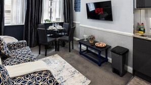 A modern living room with a dining area, a TV mounted on the wall, and a chandelier. - Stunning Super king & Double Bed Apartment|Central London|Oxford St|Bond St (London)