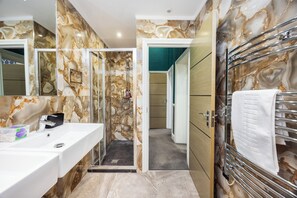 A bathroom with marble walls, a white sink, a glass shower enclosure, and a towel rack. - Stunning Super king & Double Bed Apartment|Central London|Oxford St|Bond St (London)