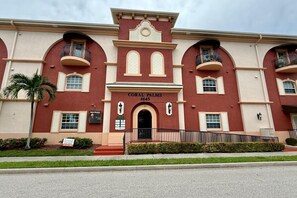 A multi-story building with a red facade, arched windows, and balconies. - Downtown Cape Coral Loft Walk to Dining and Bars (Cape Coral)